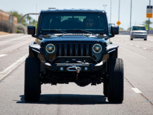 A men is driving a Black Jeep Wrangler JL