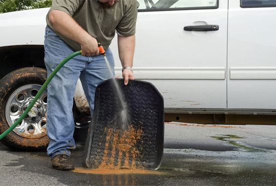 a man is cleaning his jeeps mopar all-weather floor mat
