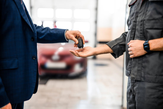 Worker receiving a car key fob from a businessman