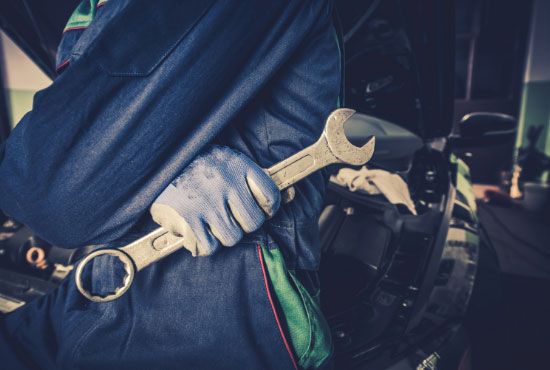 Car Mechanic with Wrench to tighten the bolts