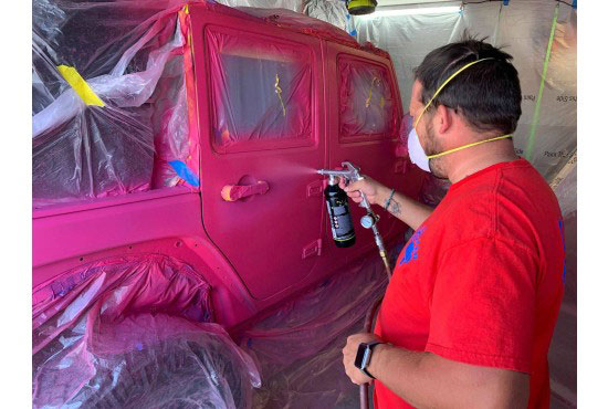 A painter painting a jeep in a paintshop